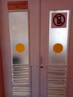 На дверях с остеклением размещены предупредительные знаки: желтые круги.
